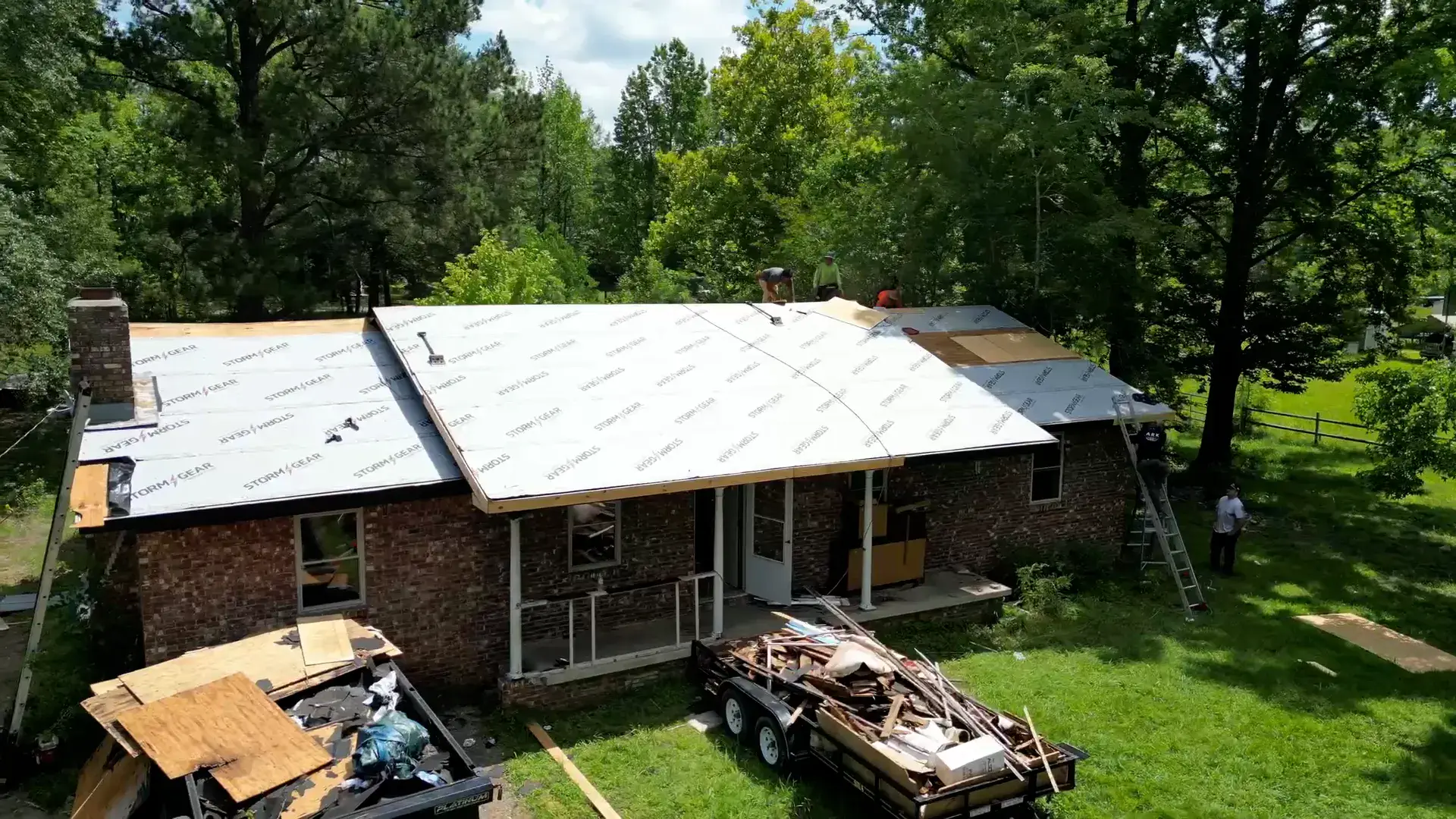 Ark Roofing crew truck and dump trailer staged in a driveway at the start of a roofing job